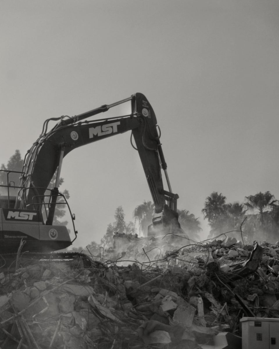 UK demolition site operative in hi-vis surveying a graded aggregate stockpile